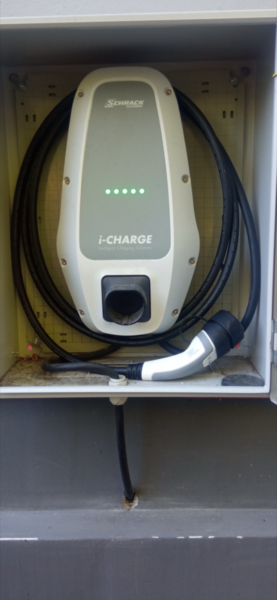 Nabíjacia stanica Schrack i-CHARGE s káblom a koncovkou Typ 2, namontovaná v uzamykateľnej skrinke na fasáde — realizácia J3M service