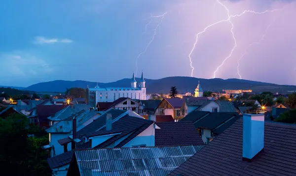 Blesky nad strechami mesta pri búrke